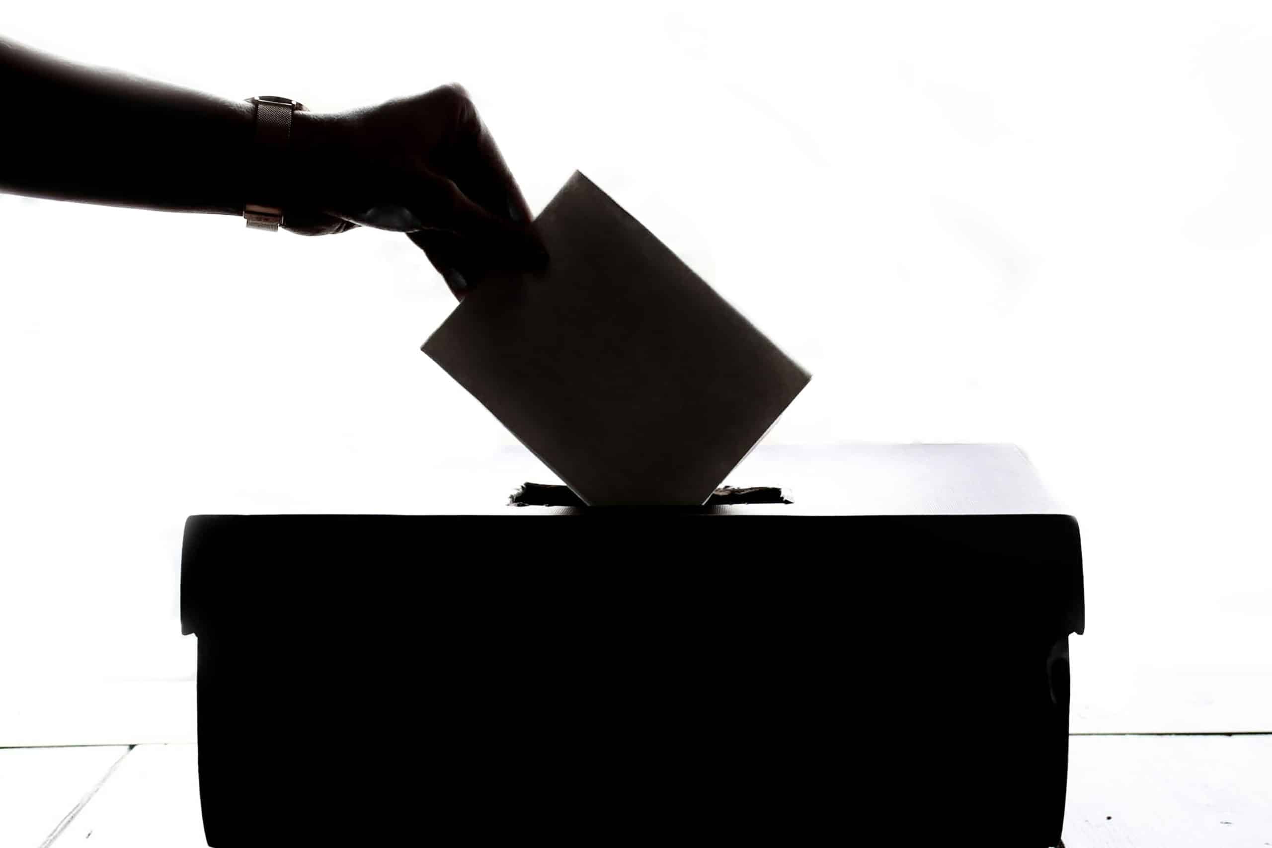 Karol Nawrocki a hand putting a piece of paper into a ballot box